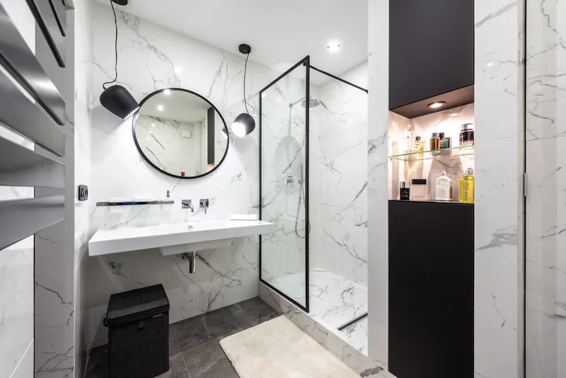 Black-frame glass shower in a white marble bathroom