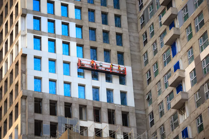Crew on a hanging platform working on a high-rise glass facade