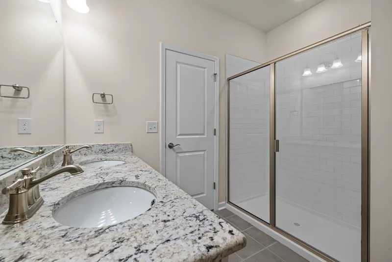 Framed sliding shower door next to a granite vanity